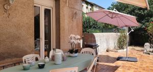 una mesa con una sombrilla rosa en el patio en La casa de Margarita y Sisco, Villa avec piscine, en Carcassonne
