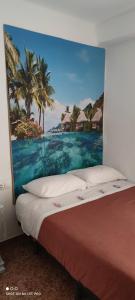 een bed met een schilderij aan de muur bij tranquilidad en el centro de la ciudad in Málaga
