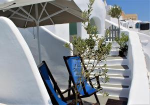 dwa niebieskie krzesła i parasol na balkonie w obiekcie Lioyerma Cave Villa With Private Outdoor Hot Tub w mieście Oia