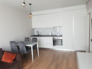 a kitchen with white cabinets and a table and chairs at Nyvky Like Home - Fayna Town - apt 398 in Kyiv