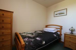 a small bedroom with a bed and a dresser at Taigh An Clachair in Lybster