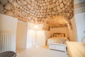 1 dormitorio con cama y pared de piedra en Trulli Margherita, intera struttura per il tuo relax, en Francavilla Fontana