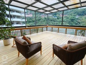 烏來區的住宿－烏來輕井澤溫泉旅館，阳台配有两把椅子,甲板上配有一张沙发