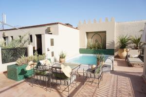 une terrasse avec une table, des chaises et une piscine dans l'établissement Riad le Clos des Arts, à Marrakech
