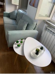 two white tables in a living room with a couch at La Torre di Borgunto - Piazza Grande in Arezzo