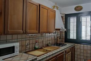 Kuchnia z drewnianymi szafkami, zlewem i kuchenką mikrofalową w obiekcie Appartamento incantevole 90 mq a due passi mare mozzafiato w mieście Isola delle Femmine