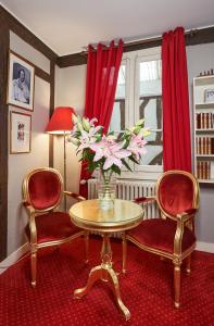 ein Wohnzimmer mit 2 Stühlen und einem Tisch mit Blumen in der Unterkunft LOGIS Hôtel Du Théâtre in Tours