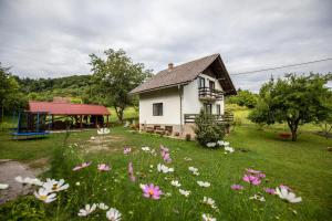 a house with a field of flowers in front of it at Holiday house On the riverside in Ogulin