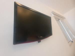 TV de pantalla plana colgada en la pared en Hostal Ayamonte Los Mellizos, en Ayamonte