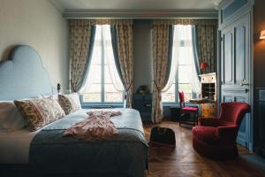 a bedroom with a bed and a chair and windows at Bayard Bellecour in Lyon