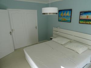 a white bedroom with a bed and a cabinet at La Rotonde in Cannes