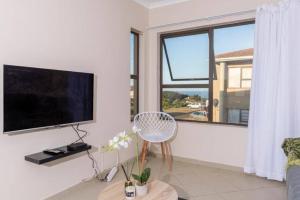 a living room with a flat screen tv and a window at Sun n Surf Sunny and spotless 1 bedroom apartment in Ballito