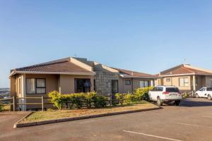 a house with a car parked in a parking lot at Sun n Surf Sunny and spotless 1 bedroom apartment in Ballito