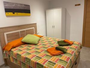 a bed with orange and green pillows on it at Apartament Margarit in Girona