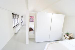 een witte slaapkamer met een grote witte kast en een bed bij Louis Henry Loft in Londerzeel