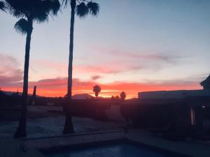 een zonsondergang met palmbomen en een zwembad bij Finca Casa Mici in Alhaurín el Grande