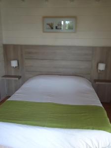 a bedroom with a white bed with a green blanket at Le Domaine du Cerf Blanc in Carentoir