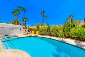 a swimming pool with chairs and palm trees at Shooting Star Permit# 3210 in Palm Springs