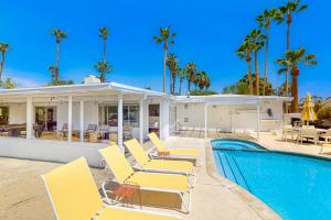 einen Pool mit Stühlen und ein Haus mit Palmen in der Unterkunft Shooting Star Permit# 3210 in Palm Springs