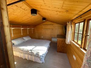 - une chambre dans une cabane en rondins avec un lit dans l'établissement 3 Bed Bungalow in Winchcombe, Cotswolds,Gloucester, à Winchcombe