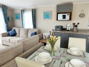 a living room with a couch and a table at Premium accommodation with luxury HOT-TUB and decking area, near Fantasy Island in Ingoldmells
