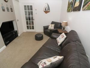 a living room with a leather couch and a television at Primrose Cottage in Hayle
