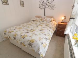 a bedroom with a bed with a floral bedspread at Primrose Cottage in Hayle