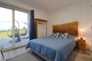 a bedroom with a bed and a large window at Casa Baleia a Vista in Algarvia