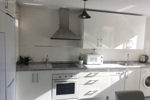 a white kitchen with a stove and a microwave at CABRIA APARTMENT in Granada