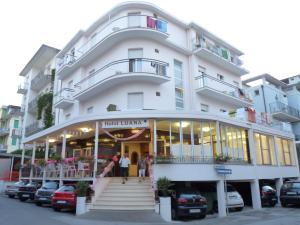 a large white building with people standing outside of it at Hotel Luana in Rimini