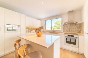 a kitchen with white cabinets and a counter with chairs at Villa Cala Mesquida in Cala Mesquida