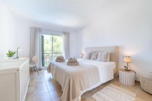 a white bedroom with a bed and a desk at Villa Cala Mesquida in Cala Mesquida