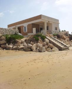 una casa en la playa con rocas delante en Villa Itaca, en Granelli