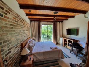 a bedroom with a bed and a brick wall at ATLANTIC FOREST ROOM in Angra dos Reis