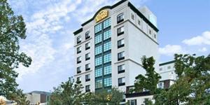 Marco LaGuardia Hotel & Suites في كوينز: مبنى طويل عليه ساعة