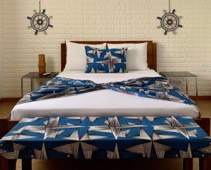 a bed with blue and white sheets and pillows at São Pedro Guesthouse in São Tomé