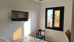 a bedroom with a tv and a chair and a window at Midpoint Raml Station (Heart of Alexandria) in Alexandria