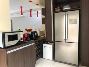 a kitchen with a refrigerator and a microwave at Solar dos Cataventos: Linda Casa com Piscina e Jacuzi in Florianópolis