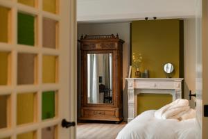 a bedroom with a fireplace and a mirror at B&B Tannerie in Balen