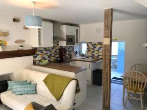 ein Wohnzimmer mit einem weißen Sofa und einer Küche in der Unterkunft Chez Claire in Excideuil