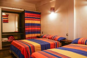 a room with two beds and a mirror at Hotel Yubazuu in San Pablo Villa de Mitla