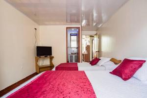 Touristic House في بوغوتا: غرفة نوم بسريرين ومخدات حمراء وتلفزيون