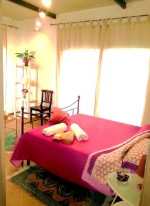 a bedroom with a pink bed with pillows on it at B&B La Greka in Condofuri