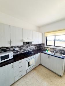 een keuken met witte kasten, een wastafel en een magnetron bij 2 bedroom townhouse, close to Paphos harbour, use of onsite facilities in Paphos City