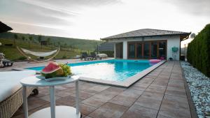 a house with a pool and a table with a watermelon on it at Villa De Luxe in Bihać