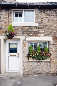 un edificio de piedra con 2 ventanas con macetas en Oh So Snug, en Whalley