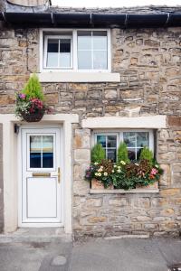 a stone building with two windows with flower boxes at Oh So Snug in Whalley