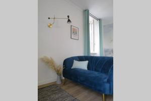 Sofá azul en la sala de estar con ventana en Dinan Château - Parking inclus, en Dinan