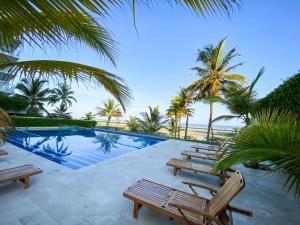 einen Pool mit Stühlen, Palmen und dem Meer in der Unterkunft Apartamento en Cartagena con vista al mar in Cartagena de Indias