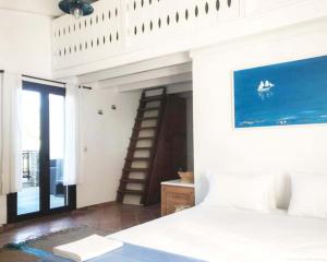 Beach Front Villa in Polychrono في هانيوتي: غرفة نوم بسرير ابيض وسلم